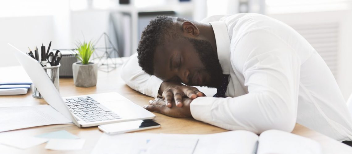 Exhausted african american young employee sleeping in his office, stress and tiredness concept, panorama with copy space